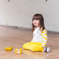 Child sitting on a wooden floor with toys nearby