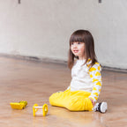 Child sitting on a wooden floor with toys nearby