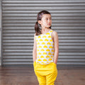 Young girl wearing a yellow outfit with cloud pattern in front of a metallic shutter.