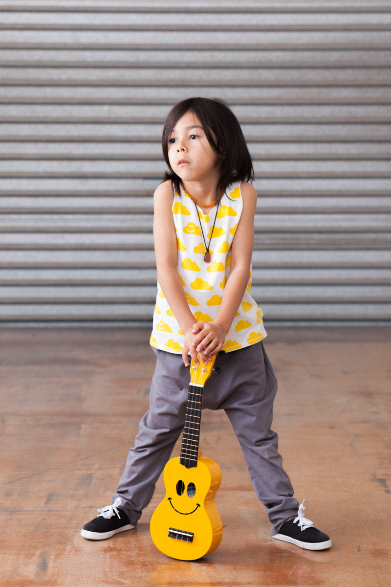 Child holding a yellow toy guitar against a metal shutter background