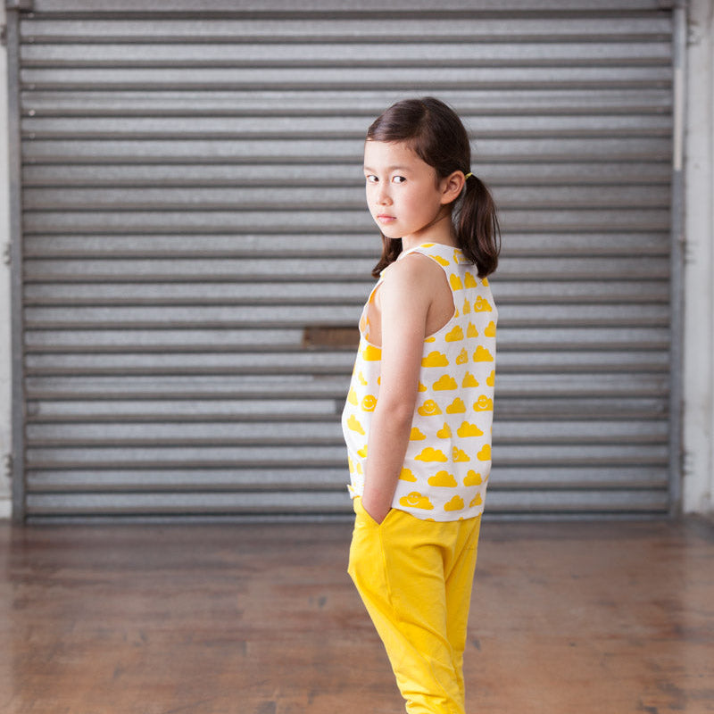 Young girl in yellow outfit standing in front of a gray shutter.