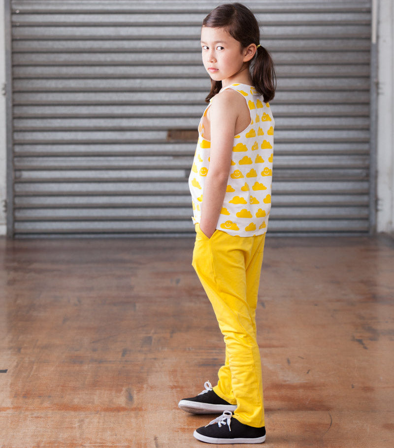 Young girl in yellow outfit standing in front of a gray shutter.