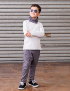 Child wearing sunglasses and a white shirt with gray pants standing in front of a metal shutter.