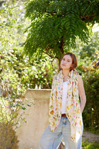 Young woman wearing the Aussie Road Trip scarf by Christie Williams standing beneath lush green trees outdoors