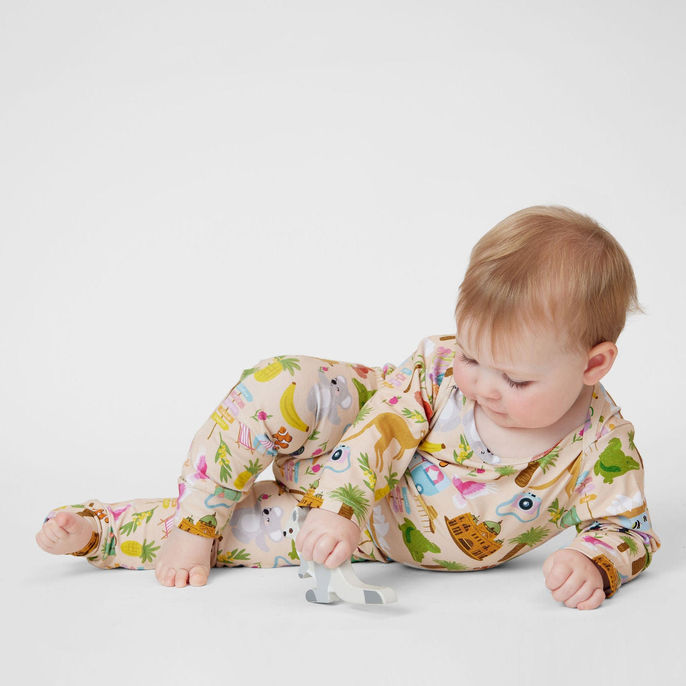 Baby wearing Aussie Road Trip Australian made organic cotton romper while playing with a wooden koala toy.