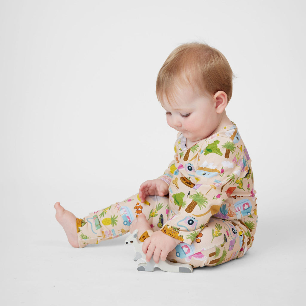 Baby wearing Aussie Road Trip Australian made organic cotton romper while sitting and playing with a wooden kangaroo toy.