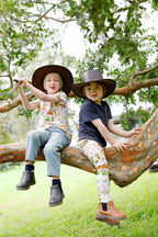 Children wearing Australian made organic cotton Aussie Road Trip outfits sitting on a tree branch outdoors