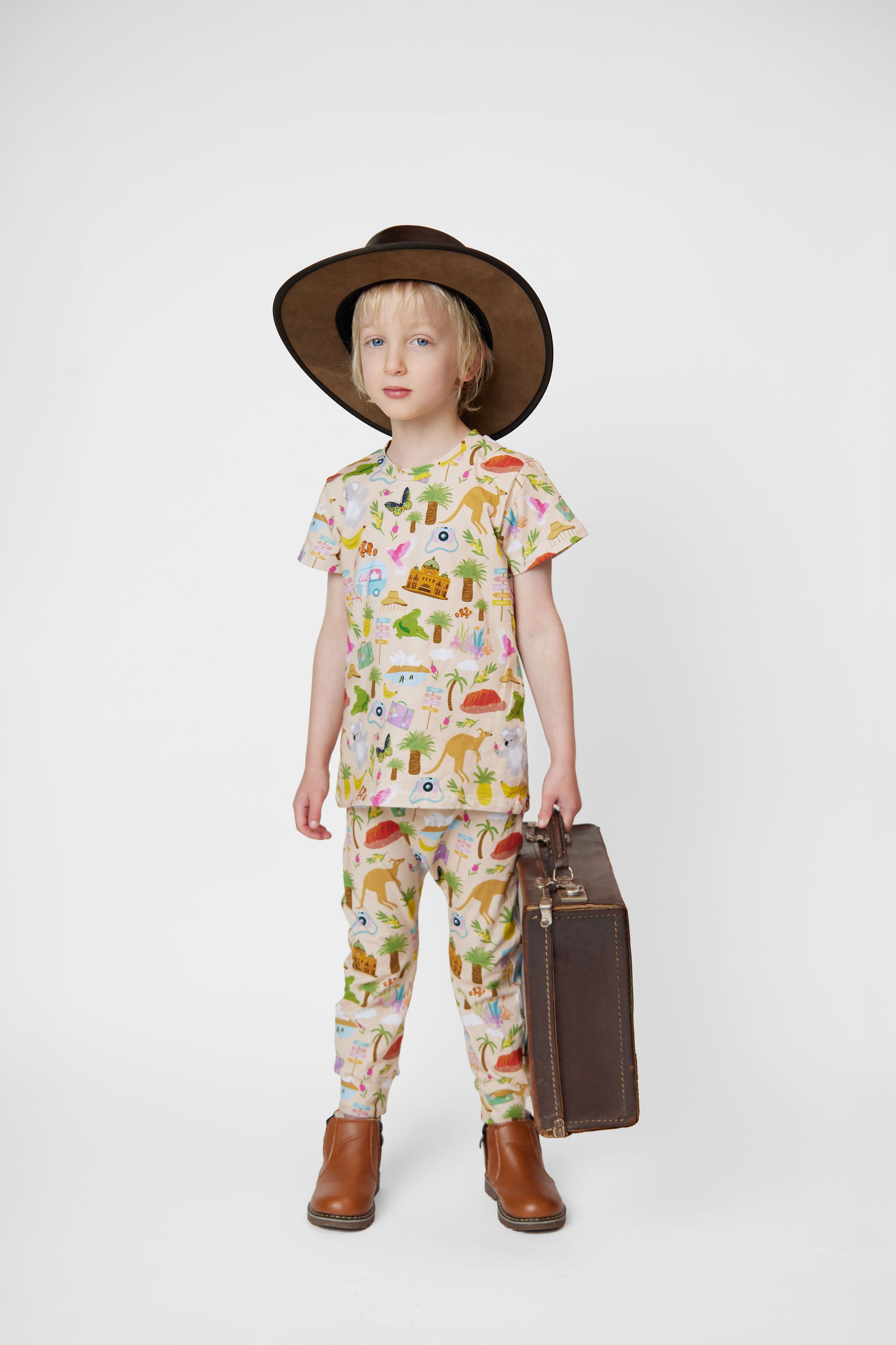 Child wearing an Australian made organic cotton Aussie Road Trip kids tee with cowboy hat and vintage suitcase
