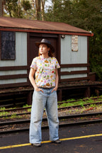 Model wearing Aussie Road Trip Australian print organic cotton t-shirt beside vintage railway building.