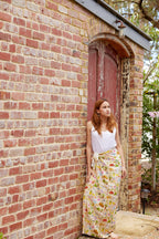 Young woman wearing the Aussie Road Trip print sarong by Christie Williams leaning against a rustic brick wall outdoors