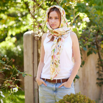 Young woman wearing the Christie Williams Aussie Road Trip scarf styled as a head wrap in a sunlit garden