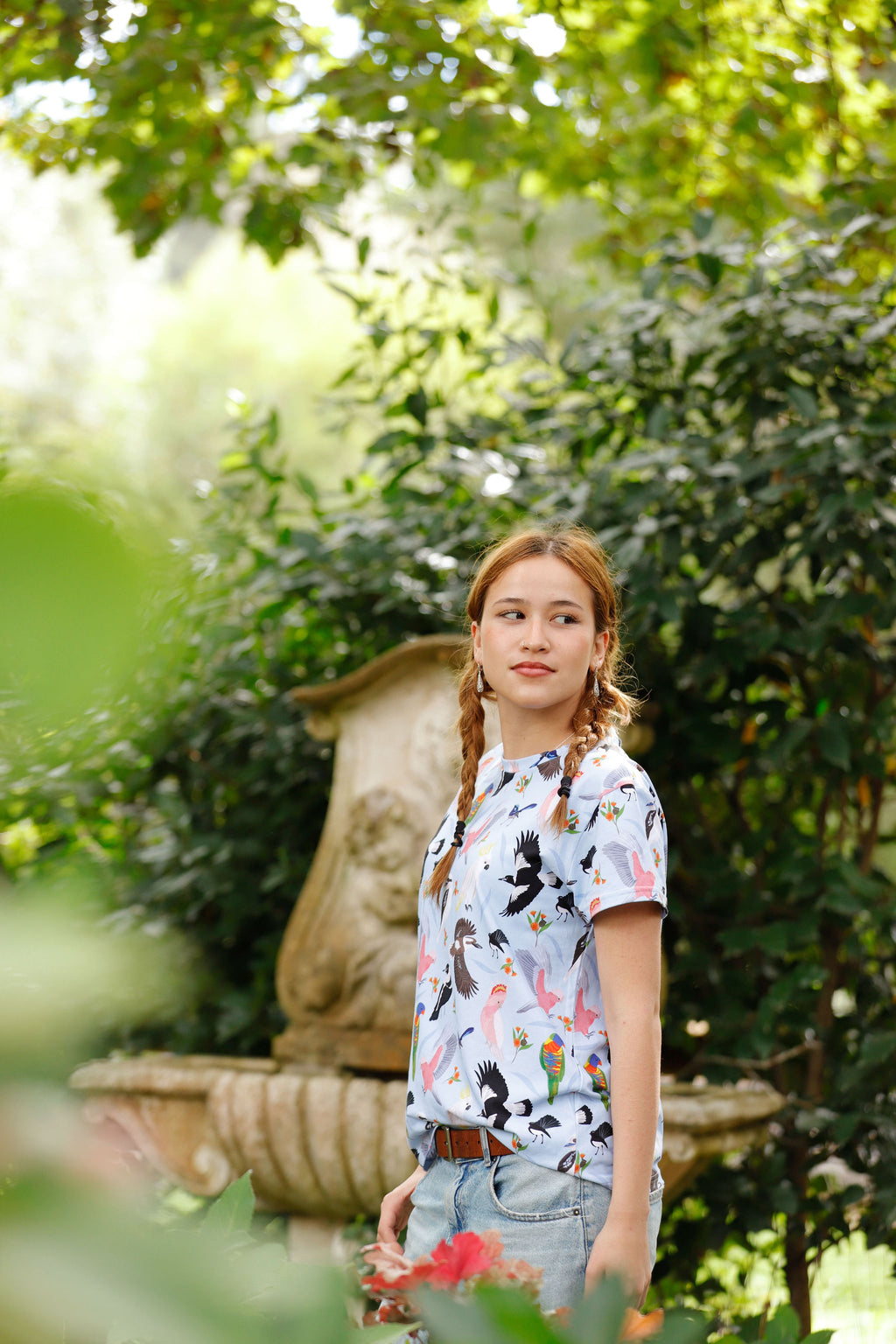 Girl wearing the Backyard Birds blue Australian bird print t-shirt by Pebble and Poppet in a garden setting