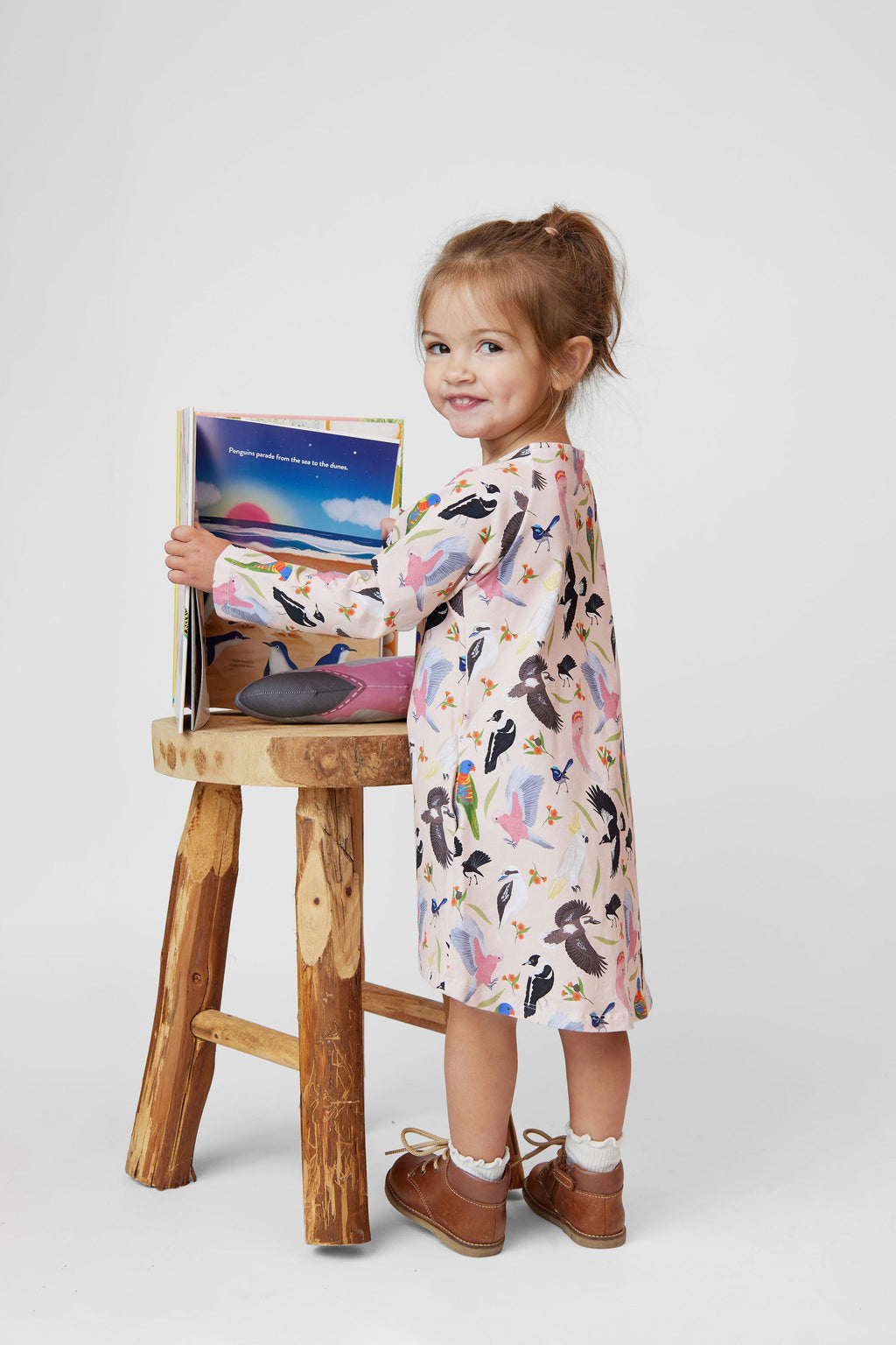 Little girl wearing blush pink Backyard Birds long sleeve dress featuring Australian native bird illustrations
