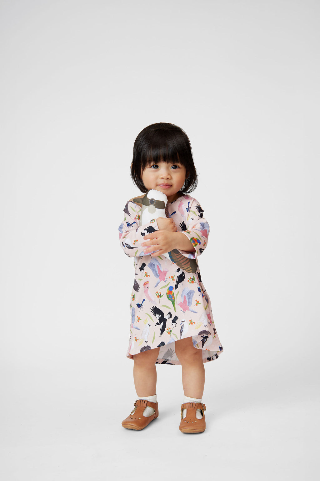 Toddler wearing Backyard Birds blush pink long sleeve dress holding bird toy