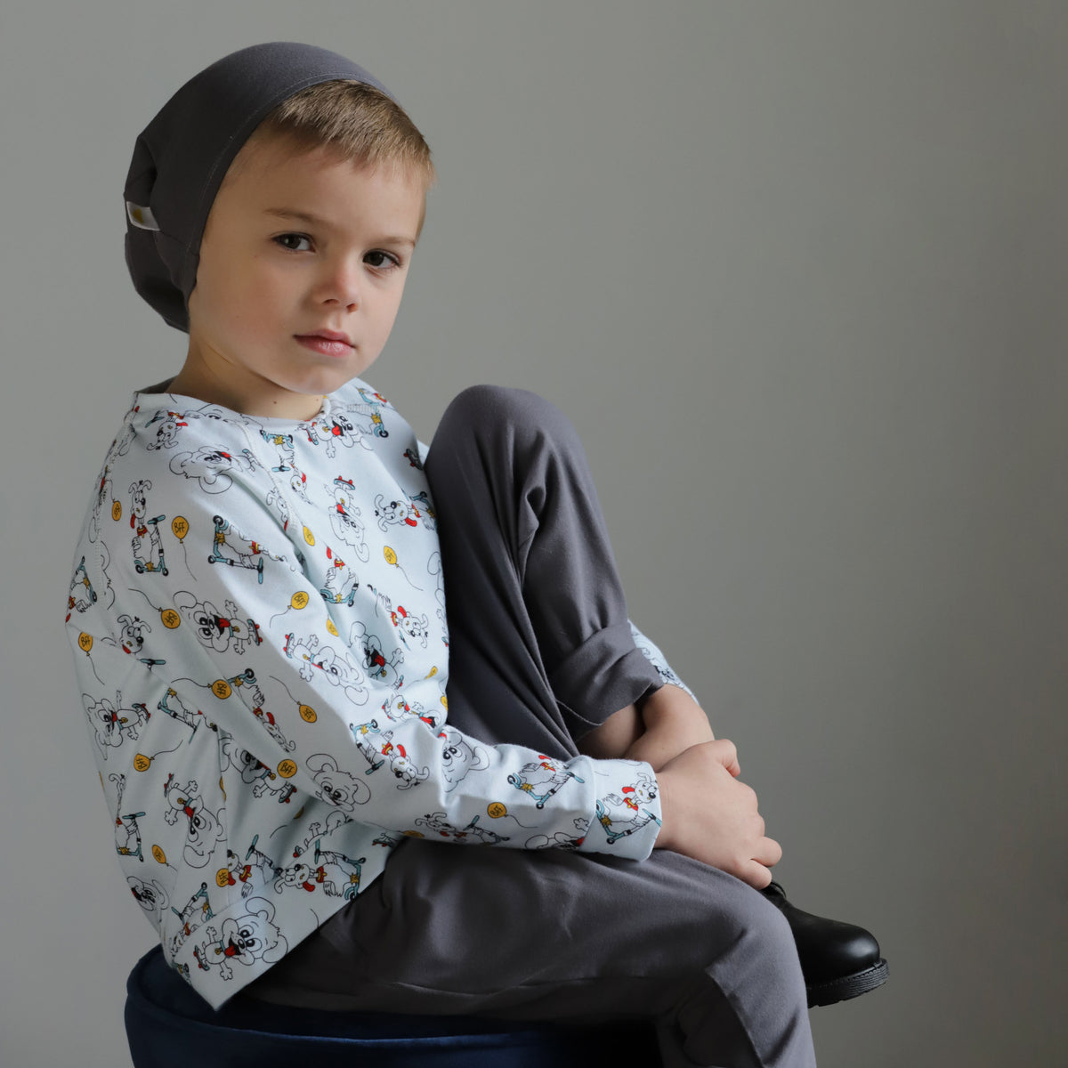 Young boy wearing an organic cotton puppy print long sleeve top with grey pants and matching beanie