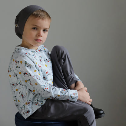 Young boy wearing an organic cotton puppy print long sleeve top with grey pants and matching beanie