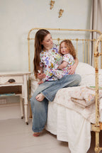 Mother and toddler wearing matching Butterfly Flora Australian made organic cotton loungewear sitting on a vintage bed