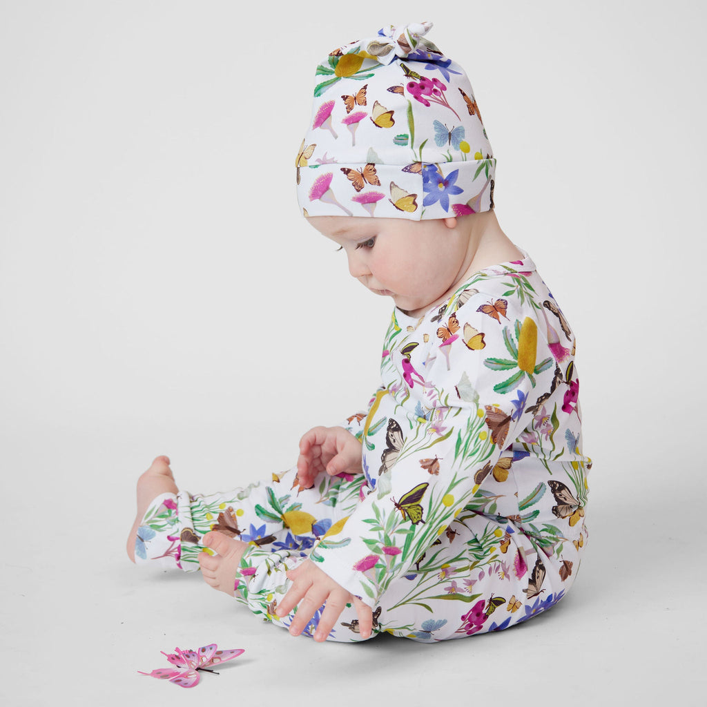 Baby sitting in Butterfly Flora Australian made organic cotton pants, matching top and knot beanie with butterfly toy.