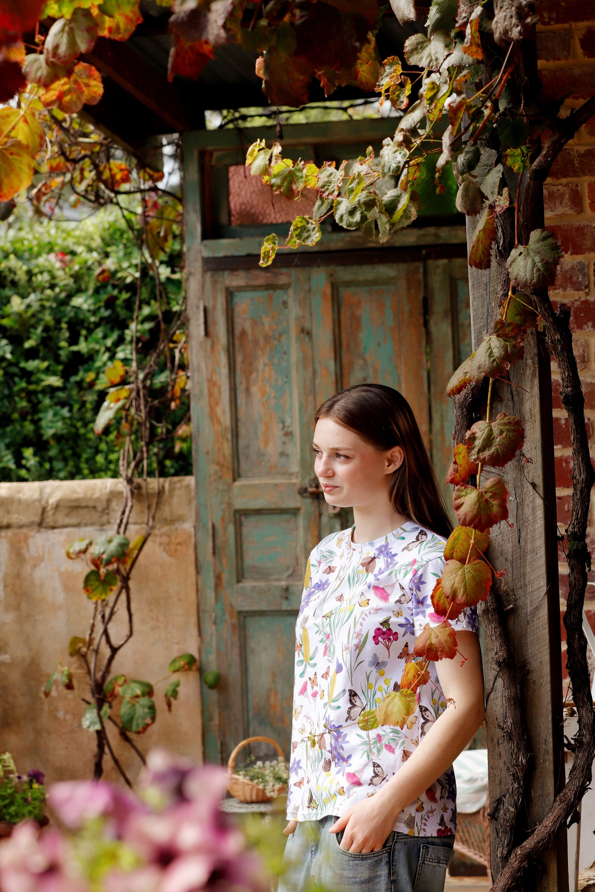 Portrait of model wearing Butterfly Flora White floral butterfly print t-shirt in vintage doorway.