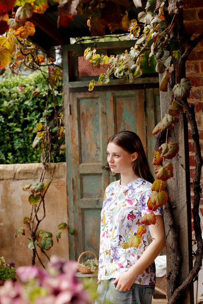 Portrait of model wearing Butterfly Flora White floral butterfly print t-shirt in vintage doorway.