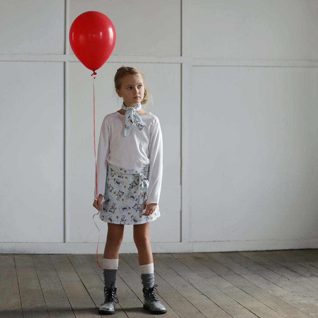 Girl holding red balloon wearing puppy print wrap skirt and matching scarf