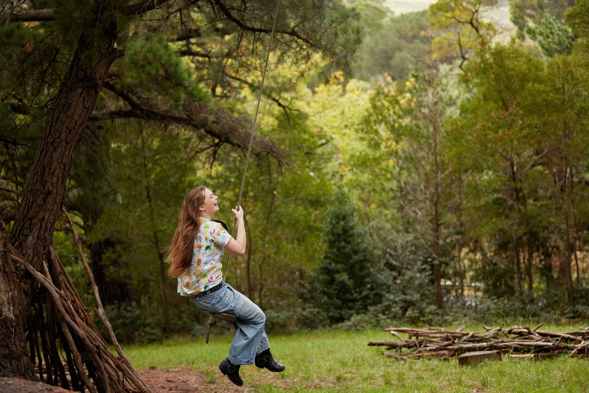 Woman wearing Summer Down Under Australian organic cotton t-shirt swinging from a rope swing outdoors.