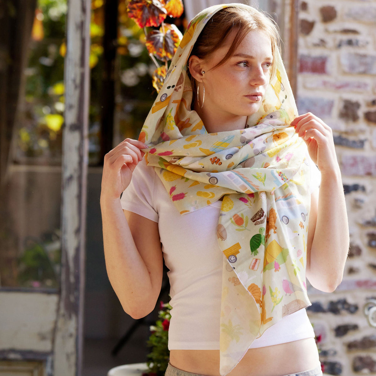 Young woman wearing the Summer Down Under bamboo scarf by Christie Williams styled as a soft headscarf outdoors