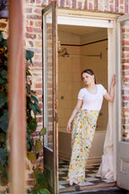 Young woman wearing the Summer Down Under bamboo scarf by Christie Williams styled as a sarong in a rustic Australian bathroom doorway