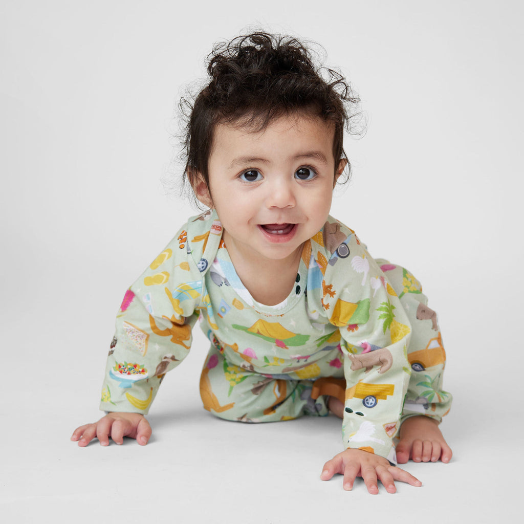 Baby crawling in Summer Down Under organic cotton romper with whimsical Australian summer print featuring caravans, kangaroos and camping icons.