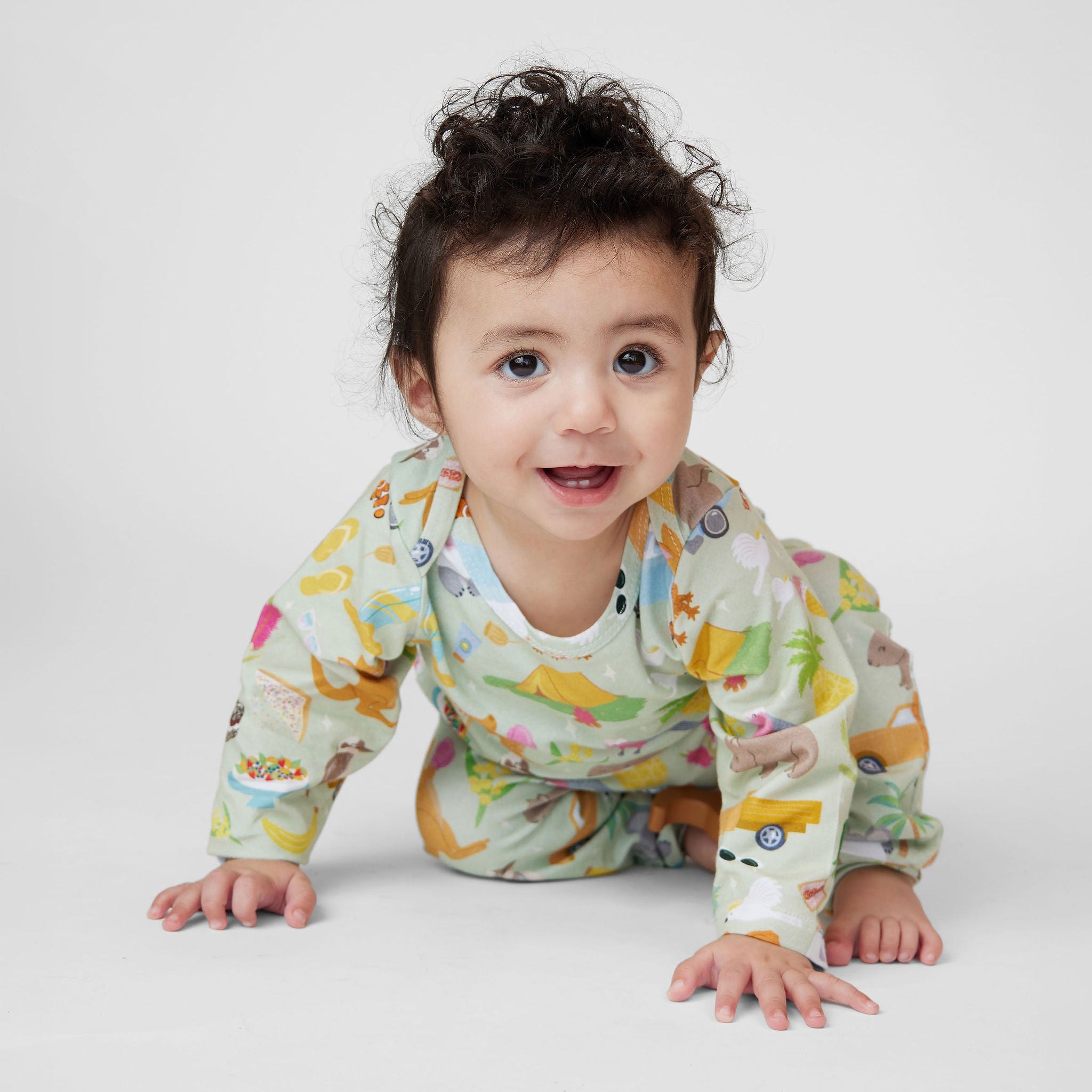 Baby crawling in Summer Down Under organic cotton romper with whimsical Australian summer print featuring caravans, kangaroos and camping icons.